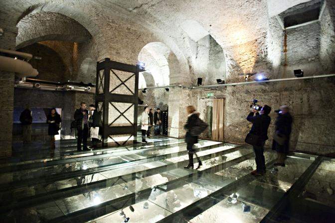 Visitors walking on the crystal floor under which you can admire the remains